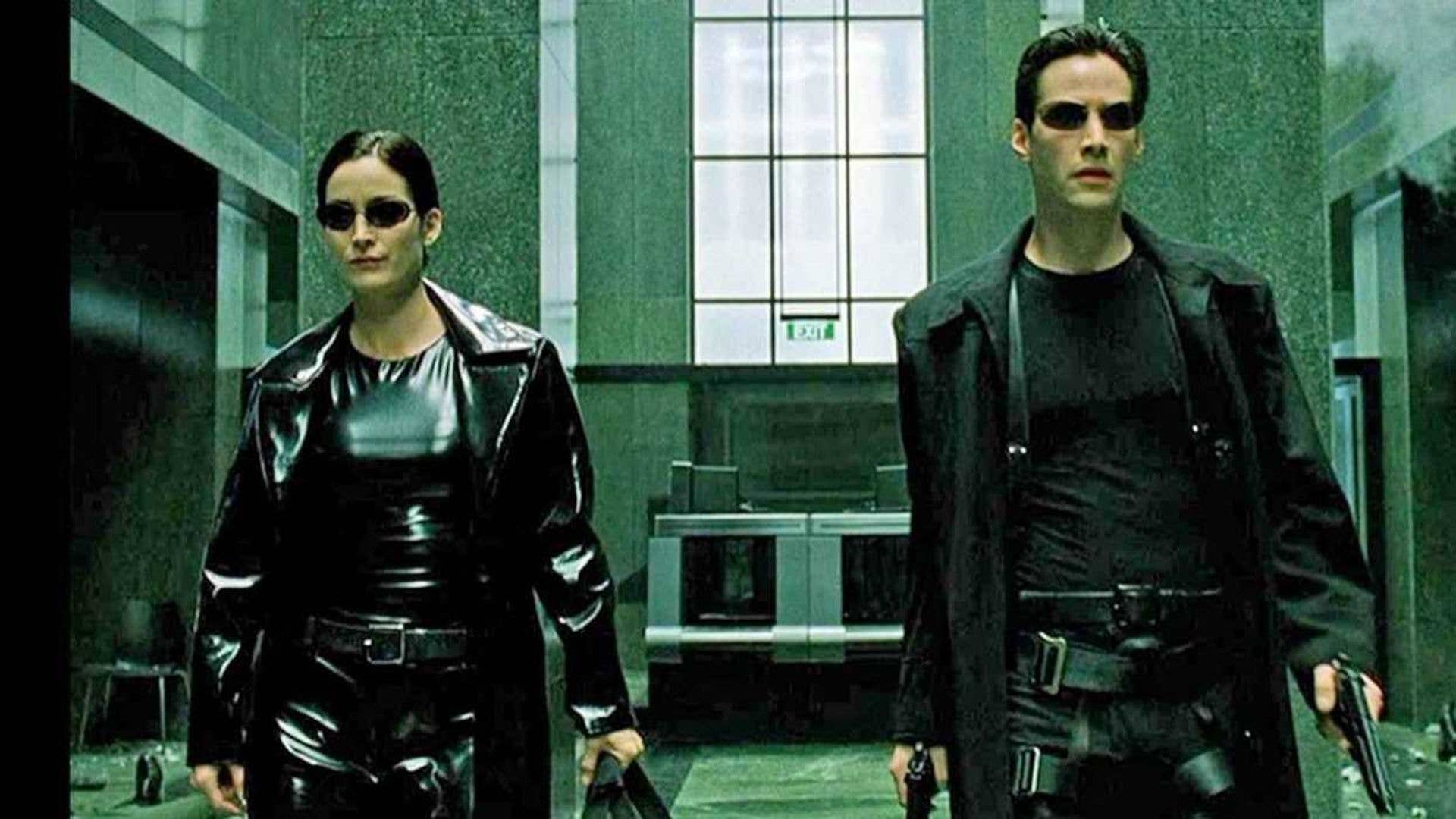 Trinity and Neo, dressed in leather and armed to the teeth, stride through an office building lobby.