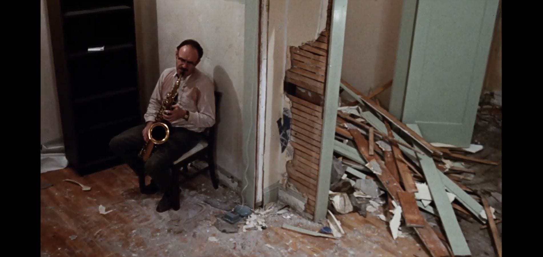 Harry Caul (Gene Hackman) sits alone in a ruined apartment, playing a saxophone.