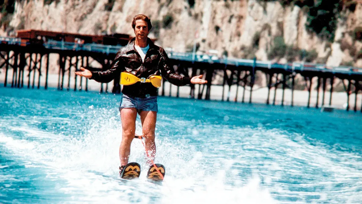 Fonzie from Happy Days glides along on waterskis, about to jump over that dang s