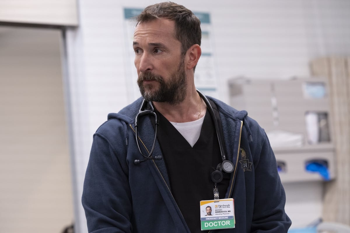 Noah Wyle stars as Michael "Robby" Robinavitch in The Pitt. Here, he looks very concerned. He has a stethoscope.