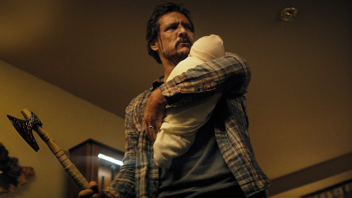 Pedro Pascal, shot from a low angle looking up, glares menacingly off-camera while clutching a bundled baby and a small axe. 