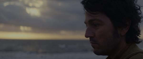 Cassian stares in a melancholy mood as the sun rises behind him. 