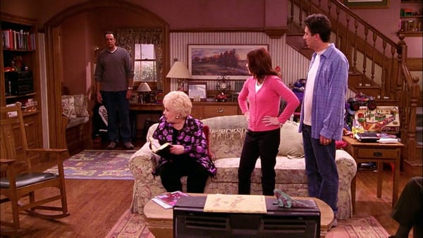 Marie (sitting, holding Bible), Debra (standing, in pink), and Ray (standing, in blue) look back at Robert, who lurks in the corner, clearly distresse