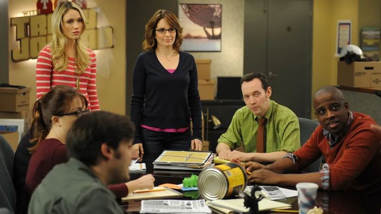 The members of the writers room in 30 Rock stare incredulously at something off-camera.