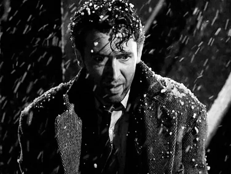 George Bailey stands on a bridge, dusted with snow, contemplating jumping off it. His eyes are wide.