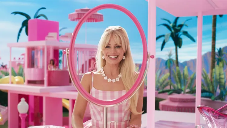Barbie, beautiful and blonde and dressed in pink, looks into a mirror that doesn't have glass in it.
