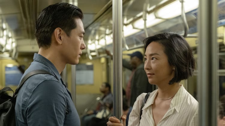 Greta Lee and Teo Yoo stare soulfully into each other's eyes on a subway in Past Lives.