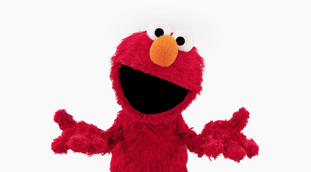 Elmo, the tiny, furry, red Muppet from Sesame Street, smiles. He's shrugging for some reason.