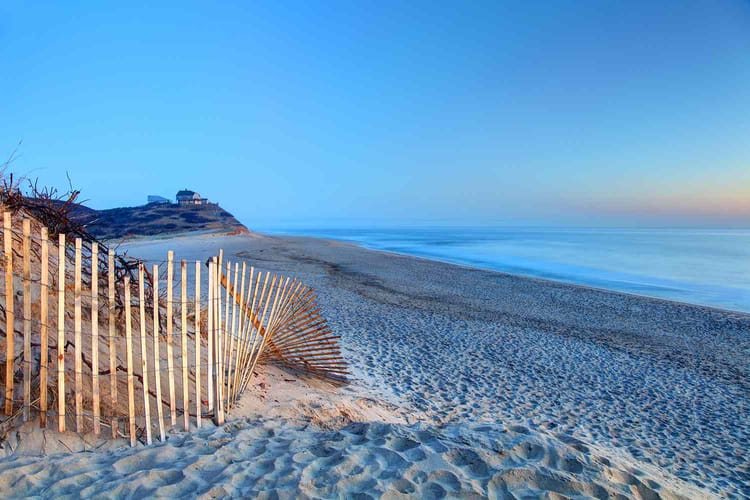 A wooden fence runs through the sand on a beautiful Atlantic beach.