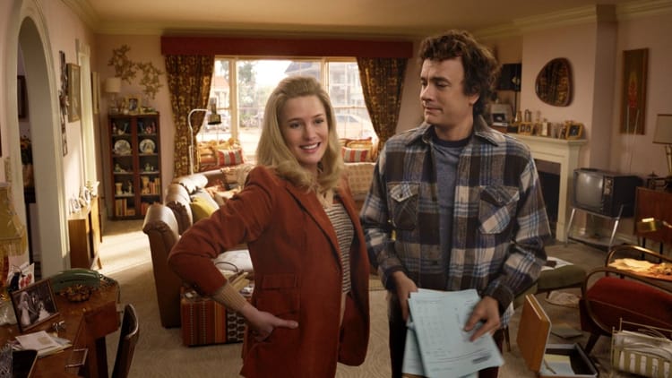 Robin Wright and Tom Hanks stand in a 1970s-ish living room. They both look subtly, creepily younger.