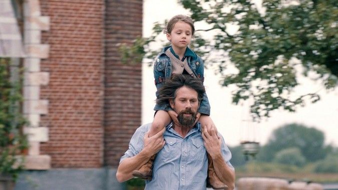 A father runs with his daughter on his shoulders in the movie The Broken Circle Breakdown.