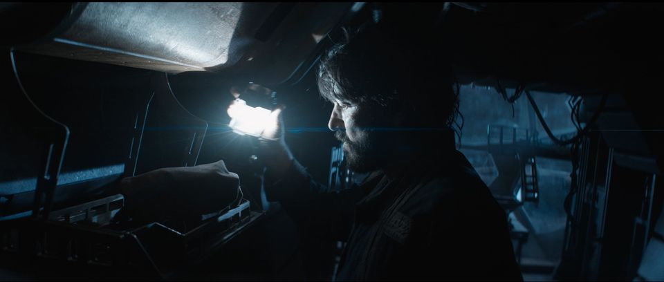 Cassian stares down at a cloth-wrapped bundle, illuminated by his lantern.