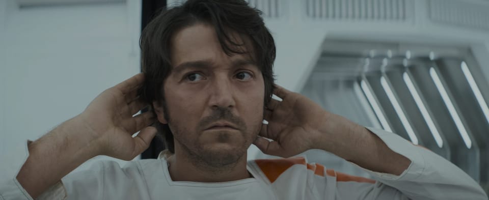 Cassian puts his hands behind his head as he takes in the work floor of the prison he's in.