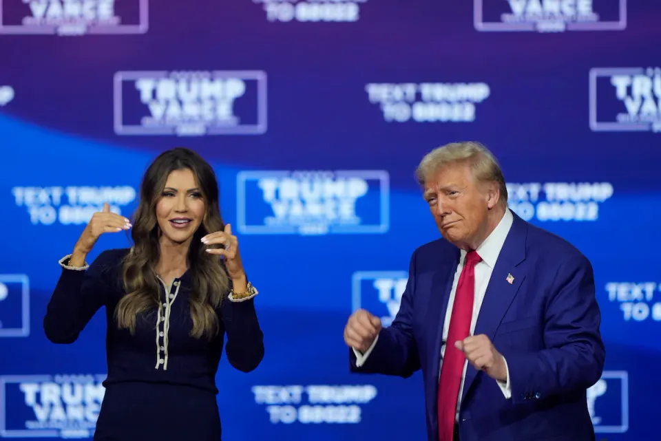 South Dakota governor Kristi Noem raises the roof while Donald Trump awkwardly dances in place.