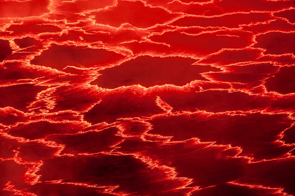 The searing orange and black surface of a still molten lava lake.