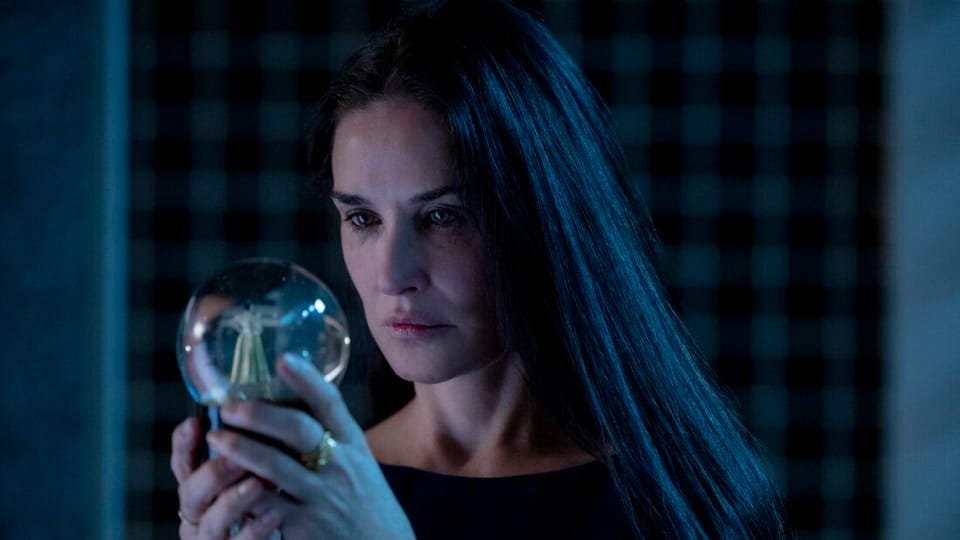 Elisabeth Sparkle, played by Demi Moore, stares into a snow globe with a ballerina dancer in it.