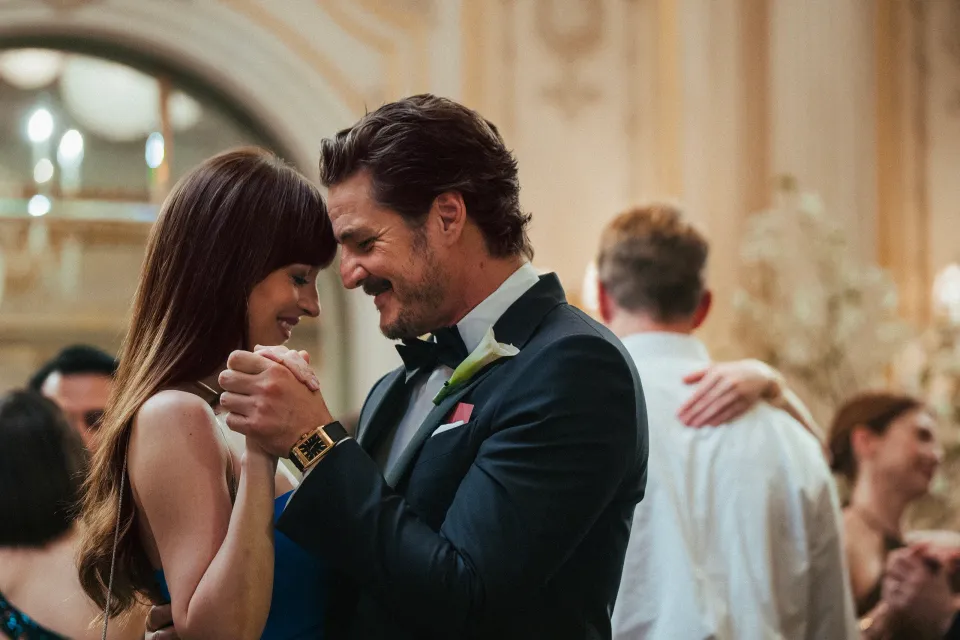 A woman and man dance at a wedding reception. He has a mustache and is wearing an expensive suit.